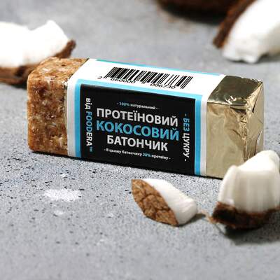 Протеїновий батончик зі смаком кокосу без доданого цукру від FOODERA у відкритій фольгованій упаковці